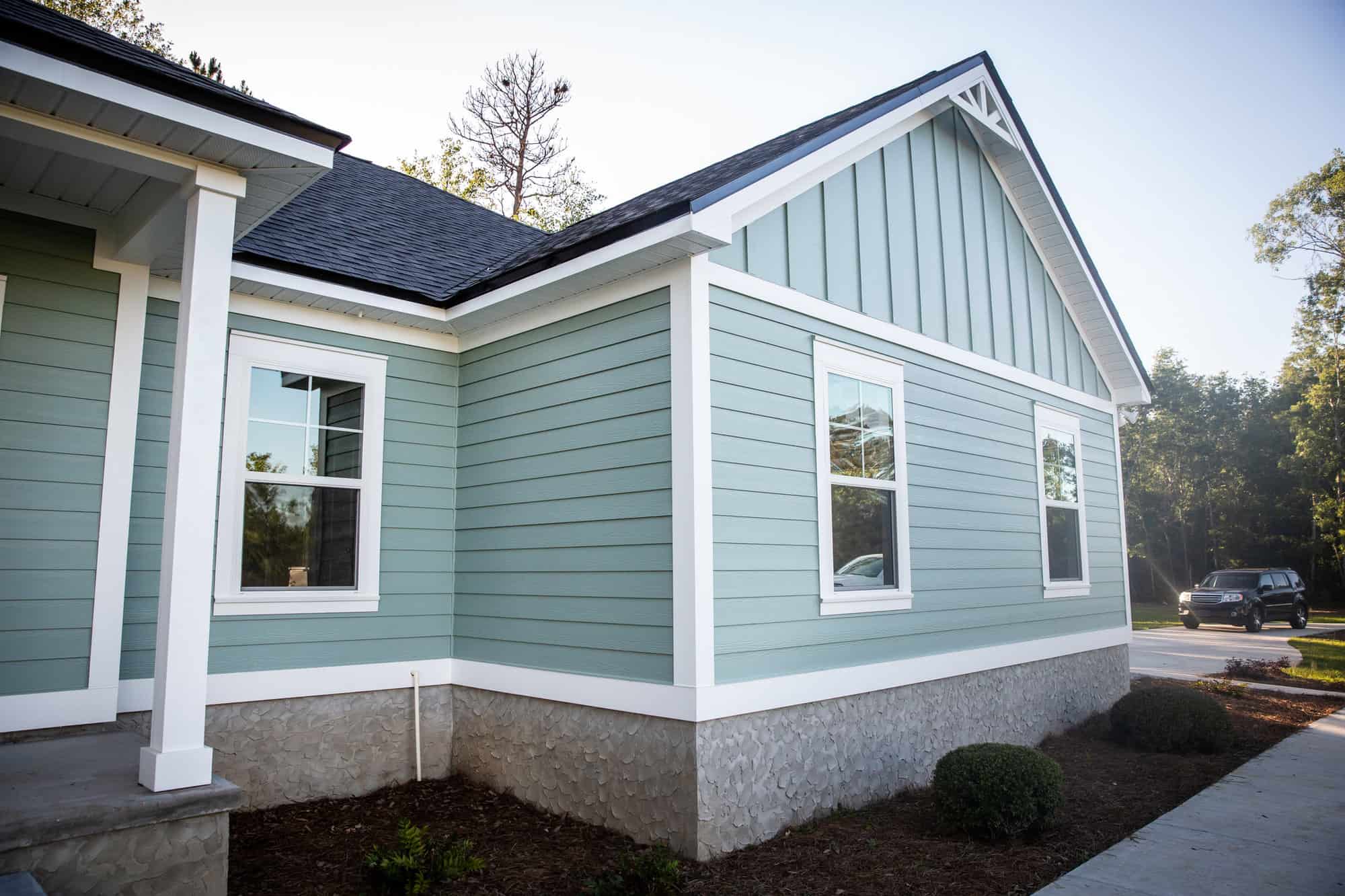 Front view of a brand new construction house with blue siding, a  ranch style home with a yard